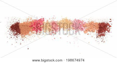 Samples of dry blush, powder, bronzers and highlighter scattered in line isolated on white background