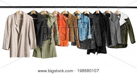 Group of coats and jackets hanging on clothes racks isolated over white