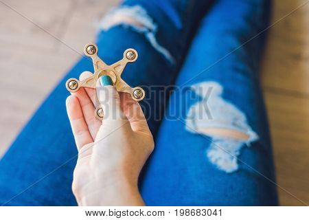 Girl Teenager In Holey Jeans Holds In Hands And Plays With Spinner