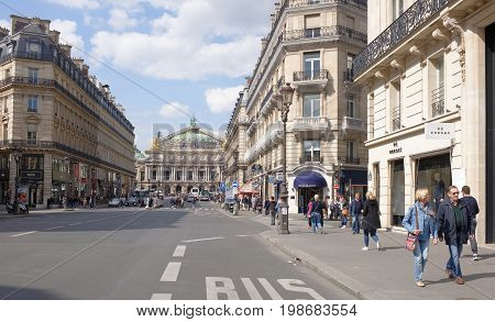 ParisFrance- April 29 2017: Scenic view of the Avenue de l Opera in Paris with the Comedie Francaise theater in the foreground and the Palais Garnier opera in the background. On the street pedestrians and moving vehicles