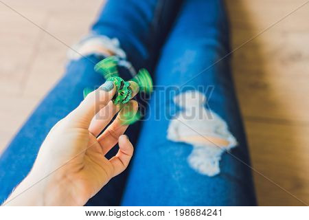 Girl Teenager In Holey Jeans Holds In Hands And Plays With Spinner