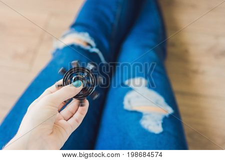 Girl Teenager In Holey Jeans Holds In Hands And Plays With Spinner