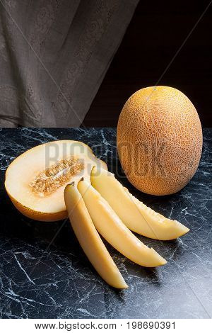 Whole, Half And Sliced Honeydew Melon Fruit On Dark Marble Background.