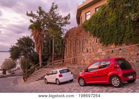 Elounda Crete Greece 19 September 2013: Two small cars near a stone wall on the shore of the Gulf of Mirabello. Crete. Greece