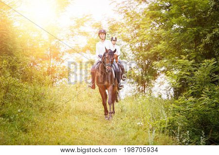 Two rider woman on horses going down from the hill. Equestrian summer activities background