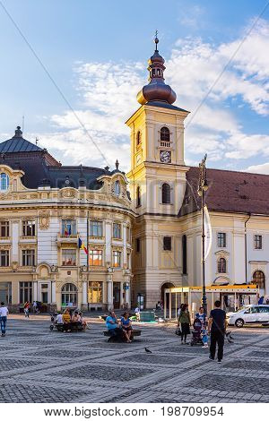SIBIU ROMANIA - JUNE 19 2017: Large main square Huet with City Hall Catholic Church tourists on the street ancient medieval city.