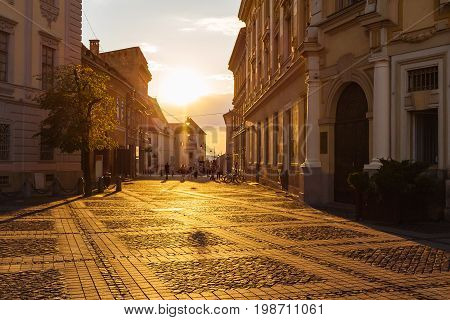Large main square Huet with City Hall and people on the street at golden sun light ancient medieval city Sibiu Romania.