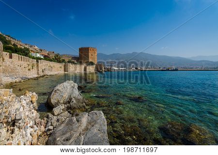 Red Tower (Kizil Kule) and the ruins of the fortress wall near the shore. The Mediterranean coast. Alanya. Turkey