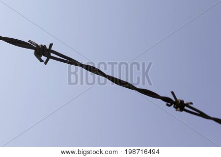Barbed wire shown against the blue sky