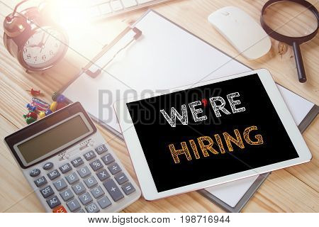 We'ar hiring text message on office tablet with office equipment. warm tone