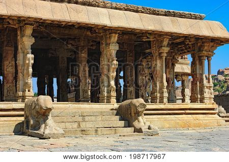 Lions in the foreground guard Bala Krishna Temple at ancient ruins of Hampi, Karnataka, India. Old and famous Indian landmark, World Heritage.