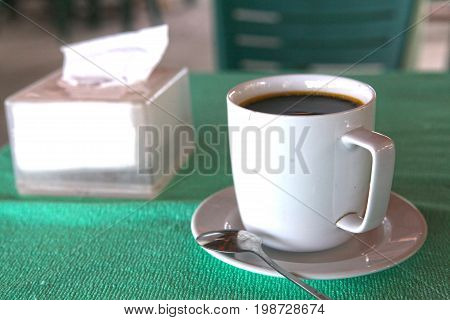 asian hot black coffee cllose up photo with teaspoon and tissue pack