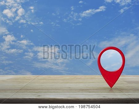 Map pin location button on wooden table over blue sky with white clouds Map pointer navigation concept