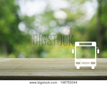 Bus flat icon on wooden table over blur green tree in park Business transportation service concept
