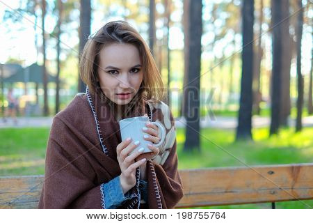 girl in a plaid drinking coffee in the park