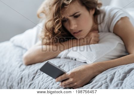 Technological device. Selective focus of a modern innovative smartphone being in hands of a nice depressed young woman while waiting for a call