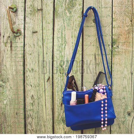 Things from open lady purse. Cosmetics and women's accessories fell out of blue handbag. Toned image.