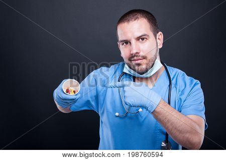 Doctor Wearing Scrubs Pointing Cup With Pills