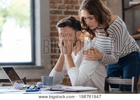 Supportive girlfriend. Caring beautiful supportive woman standing behind her boyfriend and consoling him while showing her support