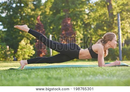 Full length shot of a beautiful fitness woman working out in the morning at the local park fit toned muscles strength balance motivation.