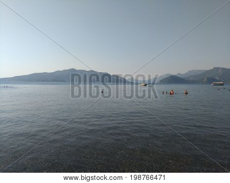 Beatiful sea summer panorama.  Beach scene at Pukka region, yachts, boats, mountains, shot at Marmaris, Turkey. blue sky, tourists in swimsuits, umbrellas, people resting, swimming