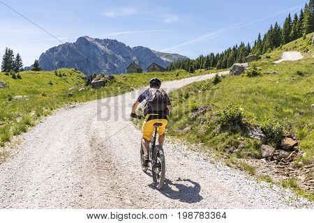 Mountainbiker on a gravel road on Nassfeld in Carnic Alps with view to mountain Rosskofel