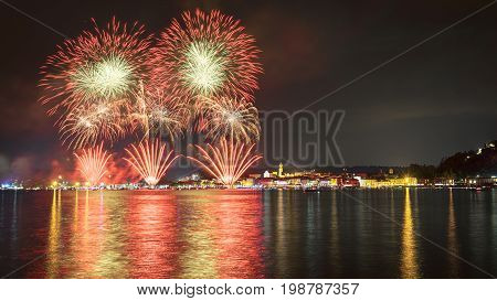 Fireworks on the lakefront of Arona over the Maggiore Lake in a summer evening with sky and clouds in the background