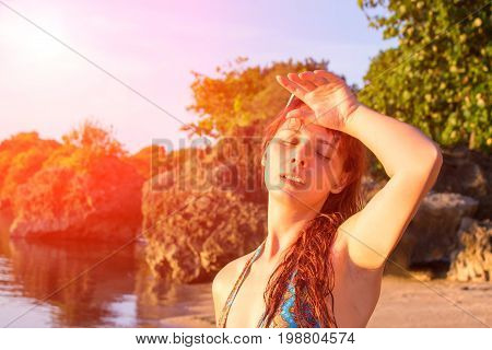 Young woman with heatstroke. Health problem on vacation. Medicine on vacation. Dangerous sun. Beach day. Sunstroke on hot beach. Vacation danger. Red hair girl on beach by sea. Holiday health care