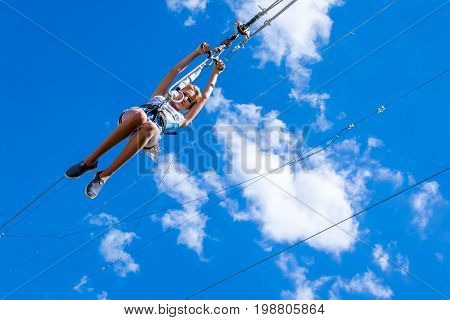 Ukraine Migea - July 30 2017: Zipline. A view of a child sliding on a steel cable against a beautiful blue sky with white clouds. Extreme and active rest.