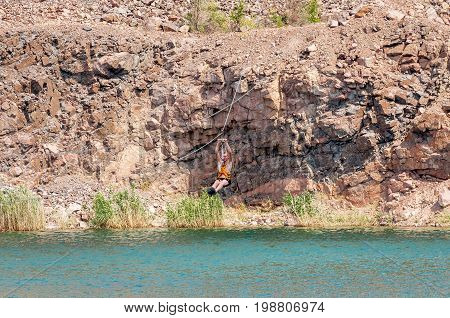 Ukraine Migea - July 30 2017: Zipline. The man in the equipment slides on a steel cable. Trolley Track Over the lake. Extreme and active rest.