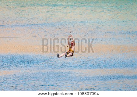 Ukraine Migea - July 30 2017: Zipline. The man in the equipment slides on a steel cable. Trolley Track Over the lake. Extreme and active rest.