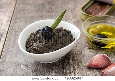 Black olive tapenade with anchovies, garlic and olive oil on wooden table