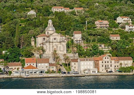 Prcanj. The town's waterfront with a long line of stone villas and the most impressive feat of architecture in Prcanj - the Birth of Our Lady church designed by a Venetian architect Bernardino Maccaruzzi. The church has a monumental baroque facade with Co