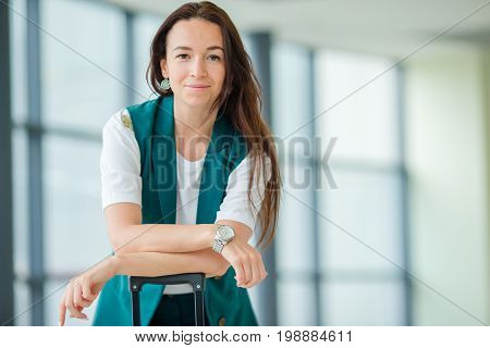 Young woman in international airport walking with her luggage.