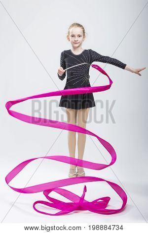 Portrait of Caucasian Female Rhythmic Gymnast In Professional Competitive Black Sparkling Starry Suit Doing Artistic Ribbon Spirals Exercises in Studio. Vertical Image