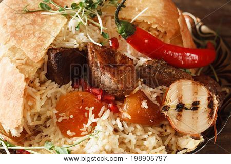 Close up of shah pilaff on big plate. National georgian cuisine, spicy rice with meat under lavash decorated chili pepper, dried apricots and grilled onion