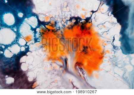 Abstract artistic image of colorful splash similar to explosion. Watercolor plumps of bright orange and dark blue colors on white background
