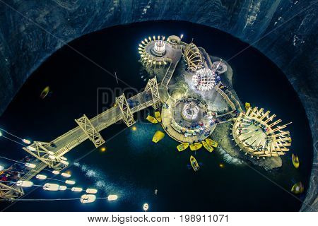 Pavilions on an artificial island in the salt lake, underground. Boat, wooden structures, the bridge leading to the island, the original rounded design and architecture. Salt mine - Solina Turda, Romania.