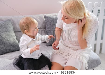 Beautiful woman and her baby playing sitting on a sofa in the white room