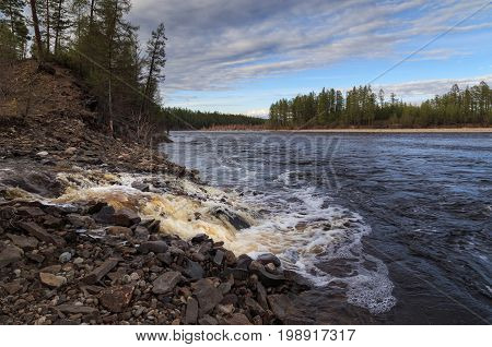 Rocky mouth of the creek which flows into the river. Evening landscape