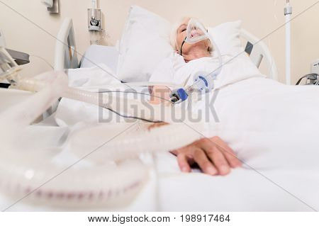 High quality services. Feeble chronic aged lady sleeping and recovering from lungs disease while the apparatus sustaining her breath
