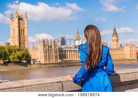 London Westminster Europe city travel urban tourist woman looking at parliament and Thames river, famous tourism attraction landmark. Autumn season people lifestyle.