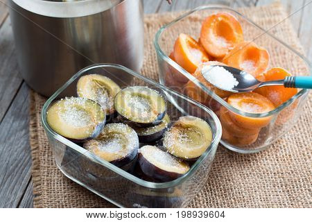Frozen apricots and plums with sugar on a wooden background