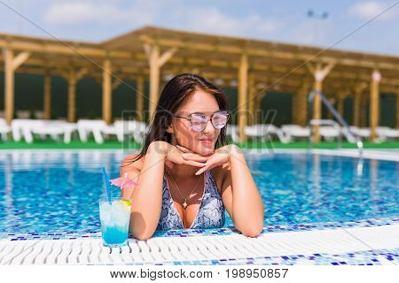 Portrait Of Young Sexy Girl Relaxing At The Edge Of The Swimming Pool., Wearing Swimsuit And Drinkin