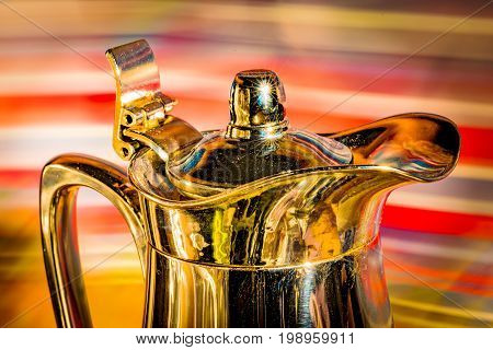 Shiny coffee pot in front of colorful background