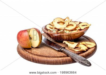 Dried apple rings lie on a board with a freshly cut apple