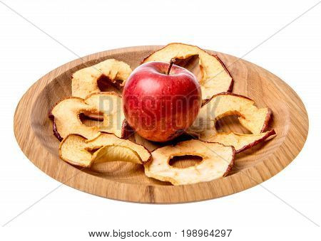 Dried apple rings lie on a board with a freshly cut apple