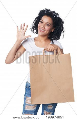 Happy mixed race woman holding craft shopping bag with blank copy space and showing five fingers