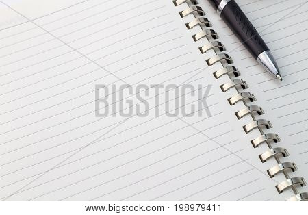 Close up view of note book with silver metal binder and pen with space for text - business background