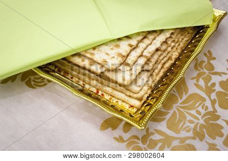 Several Pieces Of Matzoh, A Traditional Jewish Unleavened Bread On A Plate Covered With A Green Napk